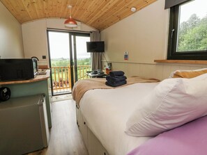 Ein Schlafzimmer mit Bett, Schreibtisch mit Computer, Fernseher und Balkon mit Blick.