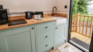 A kitchen with a sink, a coffee maker, and a microwave. - The Hut (Llandysul)