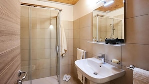 A modern bathroom with a glass shower enclosure, a white sink, and a mirror above it. - Brussa Horse Oasi (Caorle)