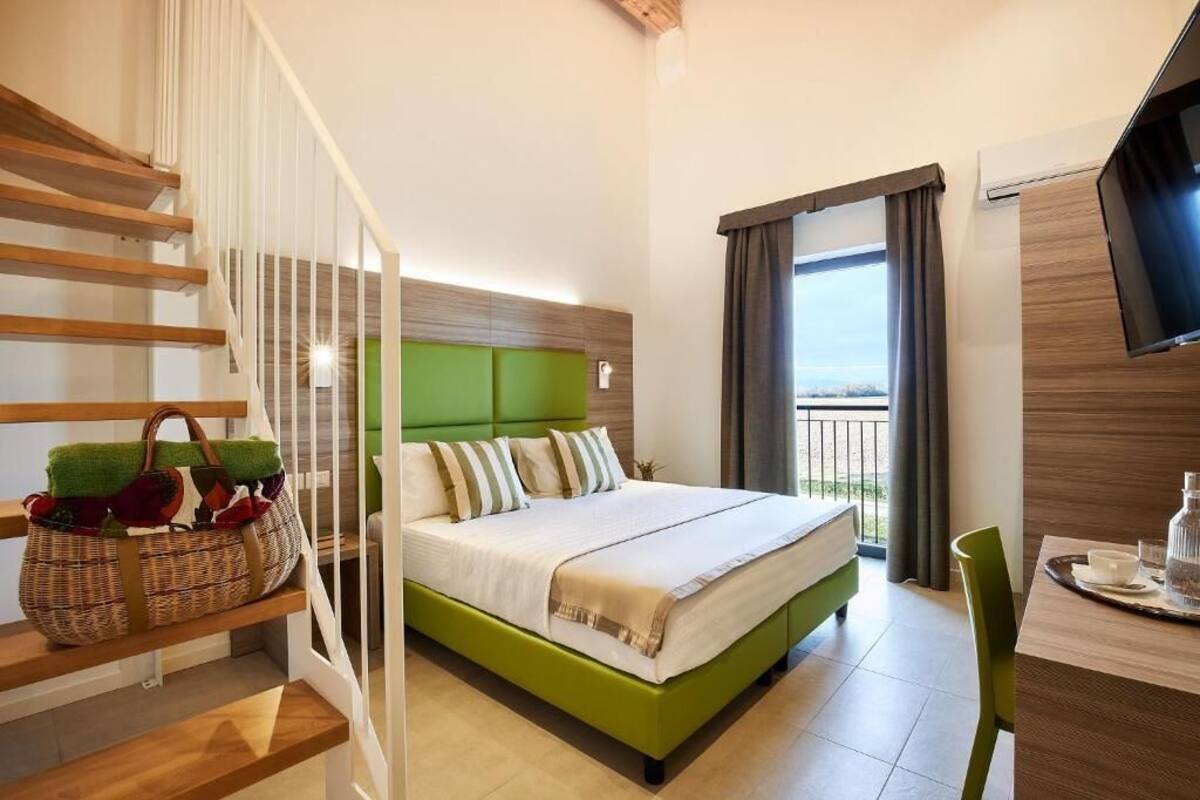 Una habitación de hotel con cama, televisión, balcón y una escalera.