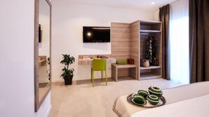 A modern hotel room with a bed, a desk, a TV, a wardrobe, and a small plant. - Brussa Horse Oasi (Caorle)