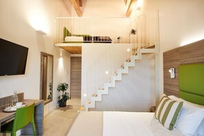 Ein Schlafzimmer mit einem Bett, einem Schreibtisch mit Stühlen, einer Treppe und einem an der Wand montierten Fernseher.