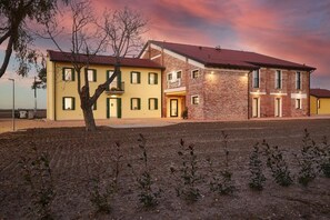 A two-story building with a brick facade and a yellow exterior. - Brussa Horse Oasi (Caorle)