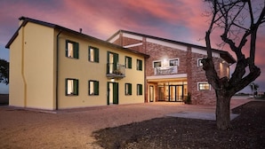 A two-story building with a yellow facade and a brick section, featuring a sign for 'Berg Horse Ölf'. - Brussa Horse Oasi (Caorle)