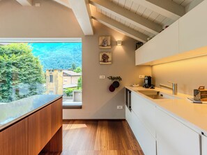 A modern kitchen with a large window, wooden cabinets, and a built-in dishwasher.