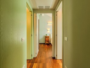 A hallway with wooden flooring, green walls, and a small bedside table with a lamp. - Apartment Zani by Interhome (Lago di Mezzola)