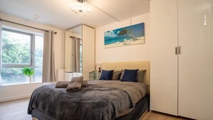 Ein Schlafzimmer mit Bett, einem Gemälde, einem Kleiderschrank und einem Fenster mit Vorhängen.