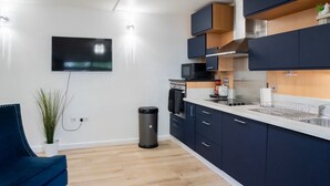 Eine moderne Küche mit dunklen Schränken, einer Mikrowelle und einem an der Wand befestigten Fernseher.
