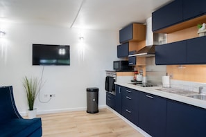 Eine moderne Küche mit dunklen Schränken, einer Mikrowelle und einem an der Wand befestigten Fernseher.