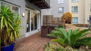 Ein Wohngebäude mit einer Holterrasse, Blumentöpfen und einem umzäunten Bereich.