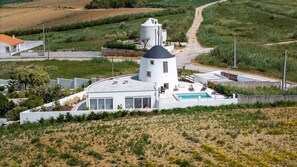 Ein modernes Haus mit einem runden Turm, einem Swimmingpool und einem umlaufenden Garten.