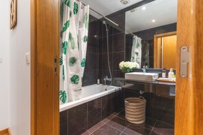 Ein modernes Badezimmer mit Badewanne, Dusche, Waschbecken und Spiegel.