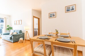 Ein Essbereich mit Holztisch, gedeckt für zwei Personen, einer Couch und einer Lampe.