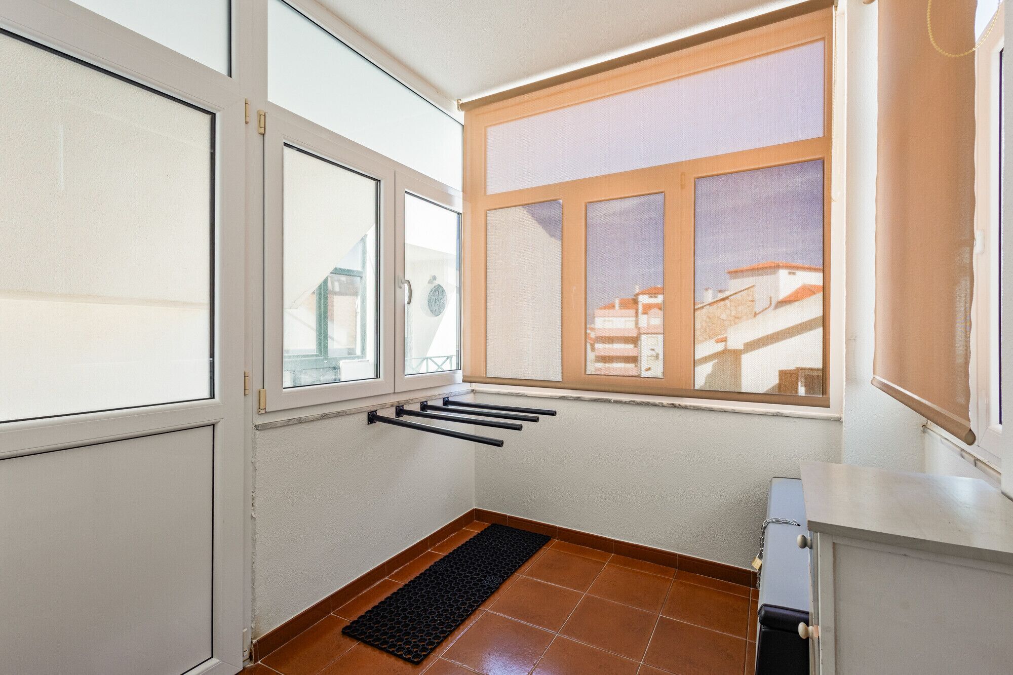 A room with a window, a door, and a black mat on the floor.