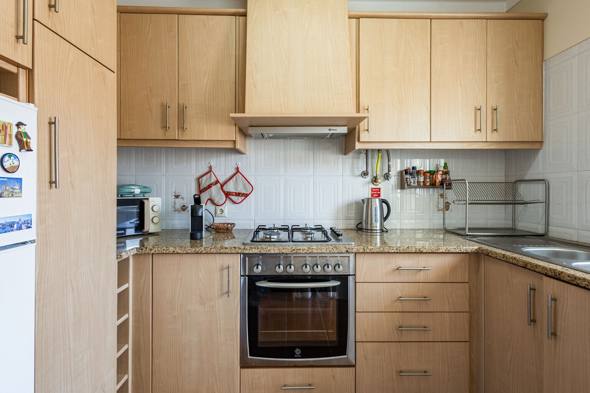 Eine Küche mit Holzausstattung, einem Gasherd, einem Backofen, einer Mikrowelle und einem Spülbecken.
