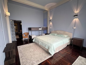 A bedroom with a bunk bed, a single bed, a chair, a nightstand, and a small cabinet. - Room With a Temple View (Bangkok)