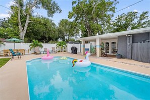 A swimming pool with inflatable toys, outdoor furniture, and a covered patio area. - HGTV Featured Home - Heated Pool, Hot Tub, Fire Pit, 5 Min Drive to Top Beaches (Largo)