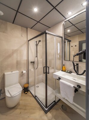 A modern bathroom with a glass-enclosed shower, a toilet, and a sink with a towel.