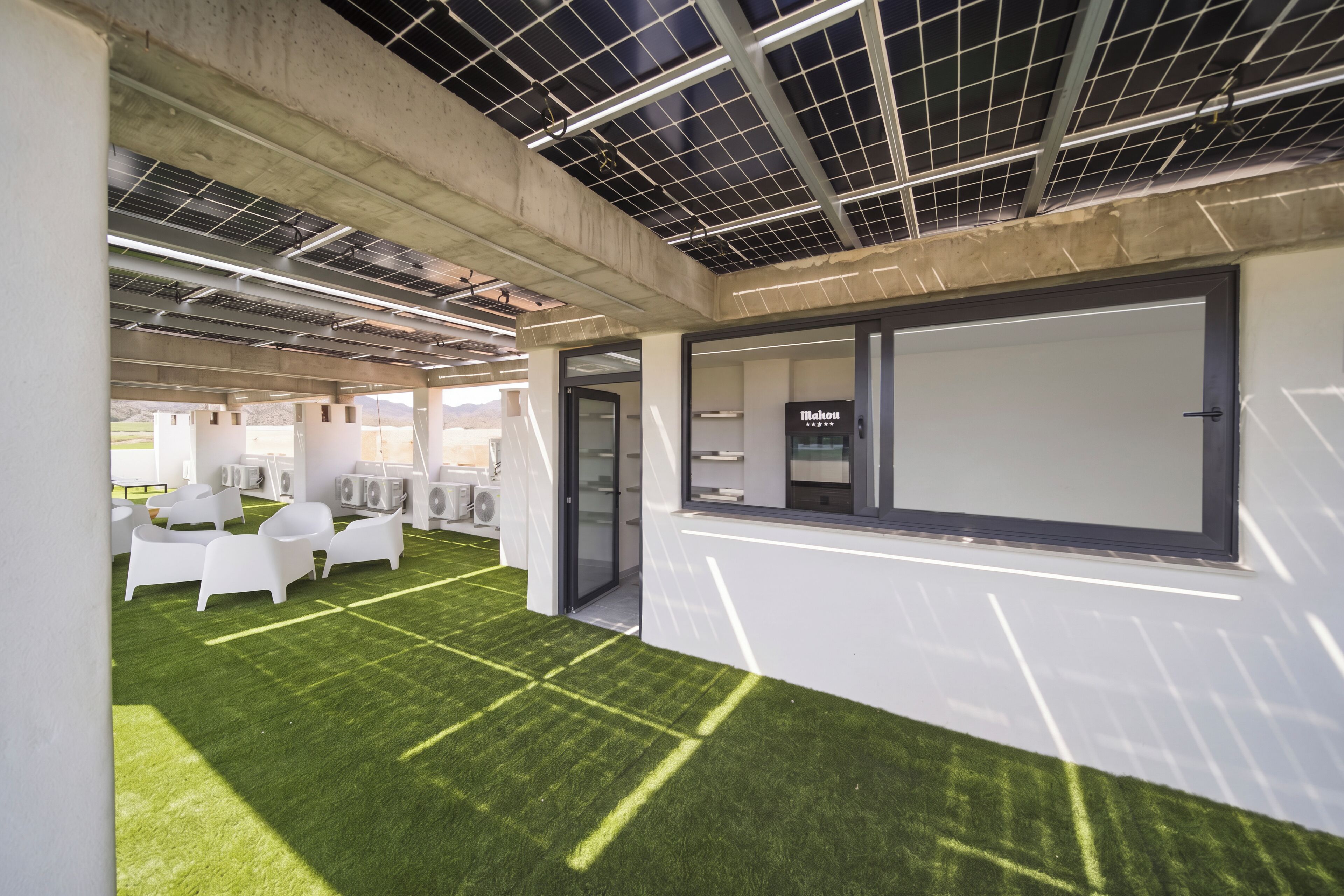 A modern indoor space with artificial grass, white furniture, and a large window with a view.
