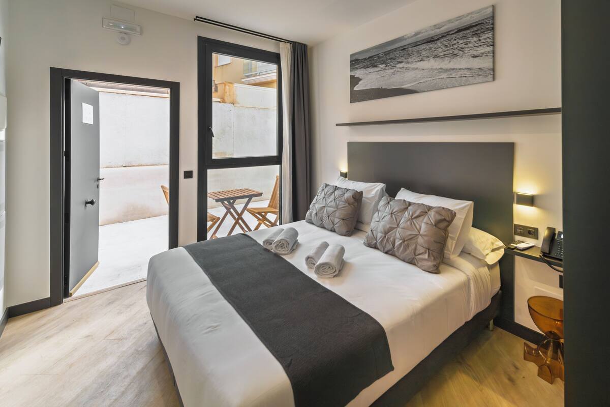 Habitación de hotel con cama, escritorio, silla y vista al exterior.