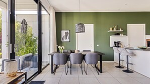 Een moderne keuken met een eethoek, een groot raam en een groene accentmuur.
