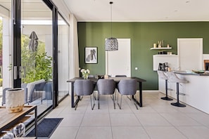 Una cocina moderna con comedor, un ventanal grande y una pared de acento verde.