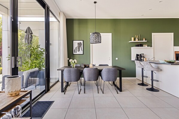 Una cocina moderna con comedor, un ventanal grande y una pared de acento verde.