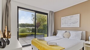 Een hotelkamer met een bed, een bureau, een kaart aan de muur en uitzicht op groen.