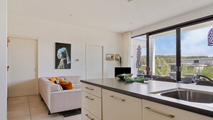 Een moderne keuken met een groot raam, een bank en een schilderij aan de muur.
