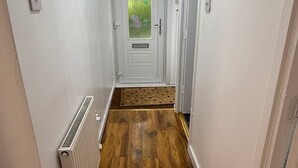 A hallway with wooden flooring, white walls, a radiator, and a door with a frosted glass panel. - Erskine - House - Sleeps 4 - Parking - River Side (Erskine)