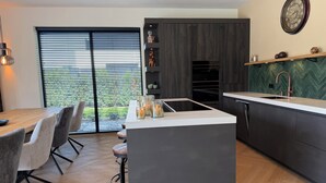 Una cocina moderna con una isla central, muebles oscuros y un salpicadero con motivo de espiga.