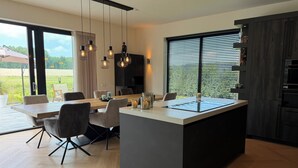 Una cocina moderna con una isla central, comedor y ventanas amplias.