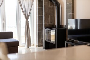 Ein modernes Wohnzimmer mit Kamin, einer Couch und einem Fernseher.
