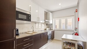 Cozinha moderna com armários escuros, micro-ondas embutido e coifa de aço inoxidável.