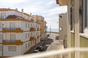 Vista de la calle con edificios de varios pisos, autos estacionados y cielo despejado.