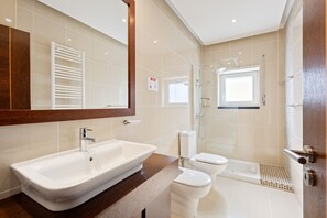 Un baño moderno con un lavamanos grande, inodoro y zona de ducha.