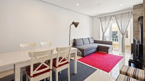 Uma sala de estar moderna com uma mesa de jantar, cadeiras, um sofá, um tapete vermelho e uma lareira.