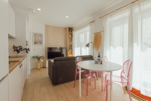 Een moderne woonkamer met een bank, een eettafel met stoelen, een televisie en een keukenhoek.