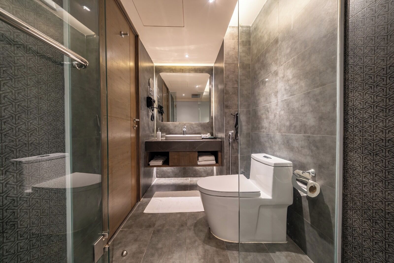A modern bathroom with a glass shower enclosure, a toilet, and a vanity with a mirror.