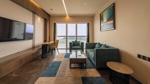Een moderne woonkamer met een flatscreen televisie, een bank, een salontafel en een eethoek met stoelen.