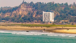 Een hotel aan de kust met uitzicht op het strand en de oceaan, omringd door heuvels.