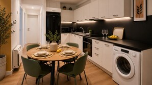 A modern kitchen with a dining area, a washing machine, and a potted plant. - LIV - Upscale Athenian Apartment 2A (Athens)