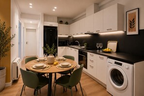 Eine moderne Küche mit Essbereich, einer Waschmaschine und einem Blumentopf.