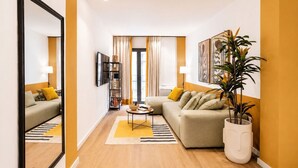 A modern living room with a sofa, a coffee table, a bookshelf, and a large mirror. - LIV - Upscale Athenian Apartment 2A (Athens)
