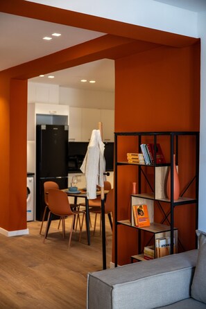 Ein modernes Wohnzimmer mit einem grauen Sofa, einem Holztisch und einem Bücherregal mit Büchern und Dekorationselementen.