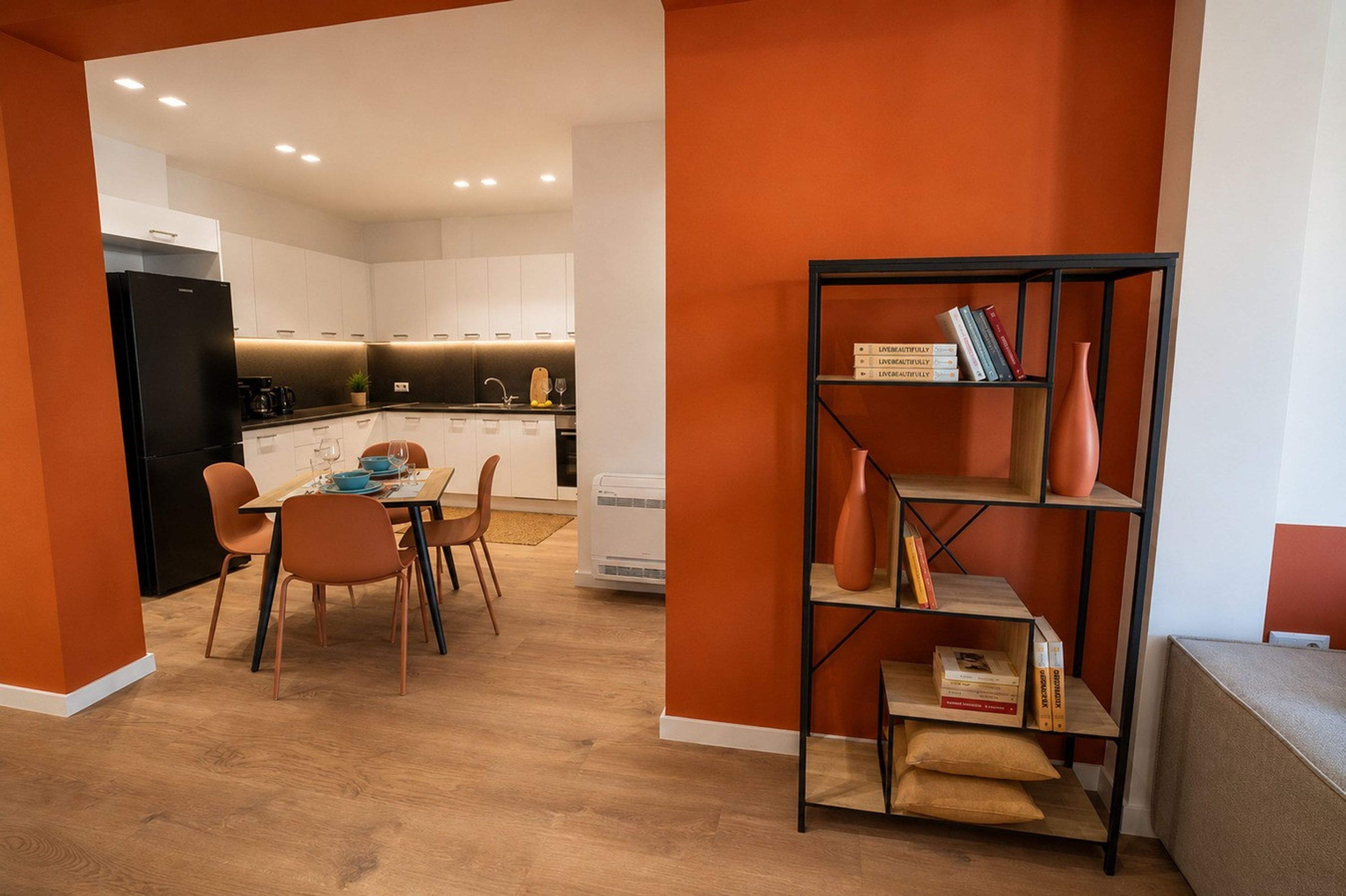 A modern kitchen with white cabinets, a black refrigerator, and a dining area with a table and chairs.