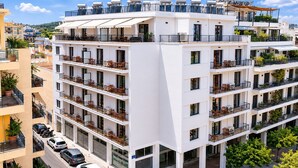 Un hôtel à plusieurs étages doté de balcons, d’un espace extérieur aménagé et d’une terrasse sur le toit.