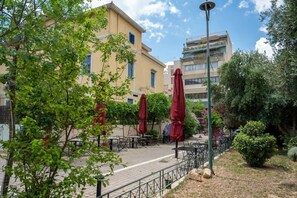 Un espace extérieur aménagé en terrasse, avec des tables et des chaises, entouré de verdure et de bâtiments.