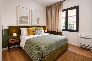 Un dormitorio ordenado con cama, mesitas de noche, una ventana con cortinas y decoración en la pared.