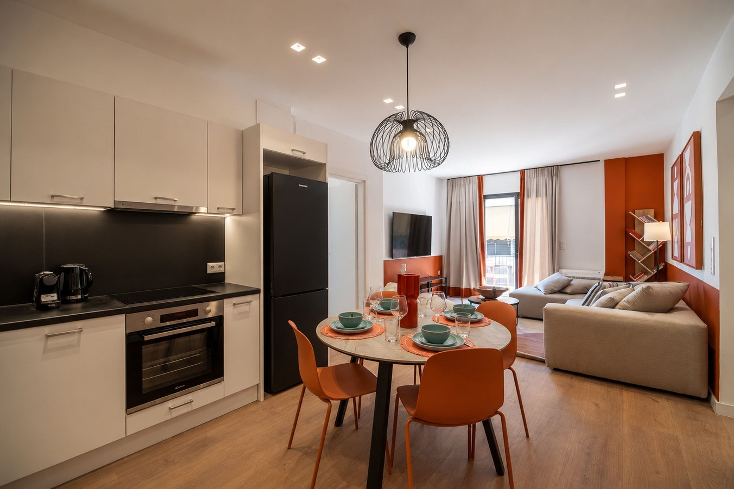 Una cocina moderna con comedor, sofá y televisor.